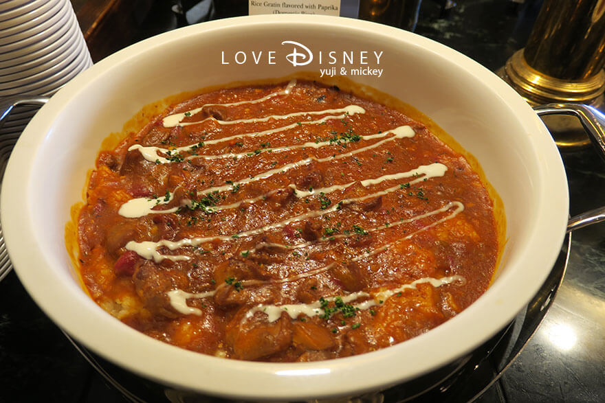 東京ディズニーランドホテル「シャーウッドガーデン・レストラン」ディズニー・パルパルーザ、ヴァネロペのスウィーツ・ポップ・ワールドブッフェ、温かい料理（チキンドリアパプリカ風味）