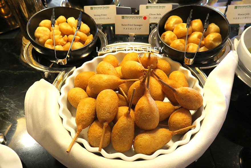 東京ディズニーランドホテル「シャーウッドガーデン・レストラン」ディズニー・パルパルーザ、ヴァネロペのスウィーツ・ポップ・ワールドブッフェ、温かい料理（アメリカンドッグ/シュリンプフリッター/チーズボール）