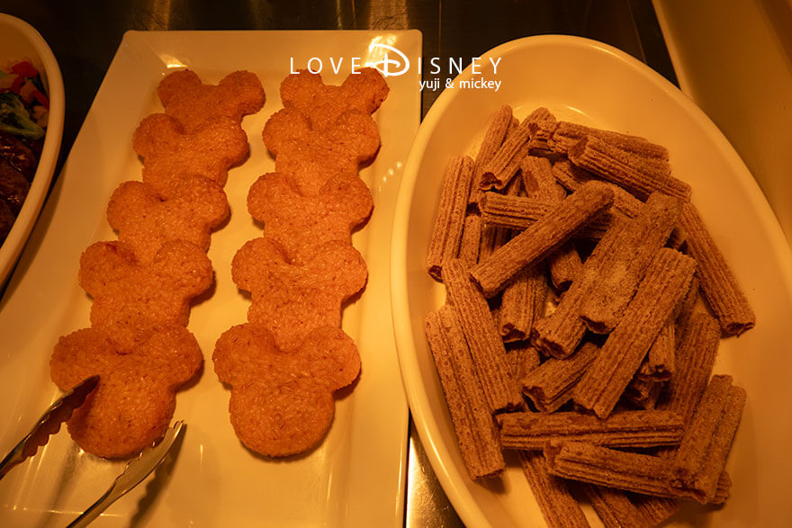 東京ディズニーランド、クリスタルパレス・レストラン「ディズニー・パルパルーザ、ヴァネロペのスウィーツ・ポップ・ワールド」温かい料理（ミッキーシェイプライス/ミッキーチュロス）